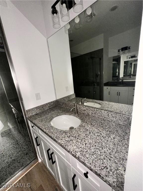 bathroom featuring hardwood / wood-style floors, vanity, and walk in shower