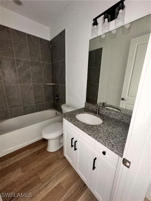 full bathroom featuring vanity, hardwood / wood-style flooring, toilet, and tiled shower / bath