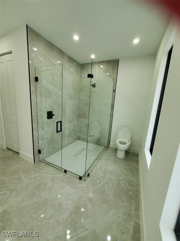 bathroom featuring toilet and a shower with shower door