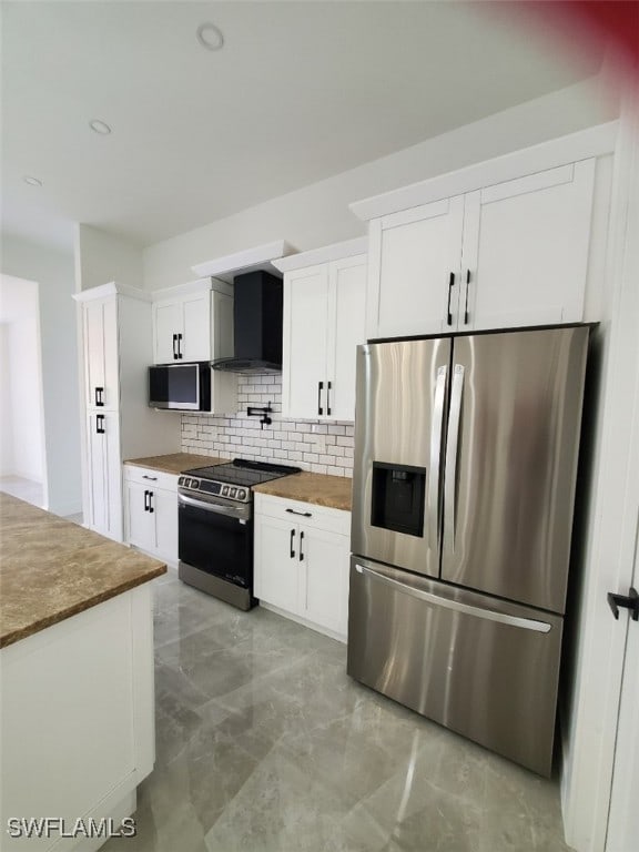 kitchen featuring white cabinets, wall chimney exhaust hood, stainless steel appliances, and tasteful backsplash