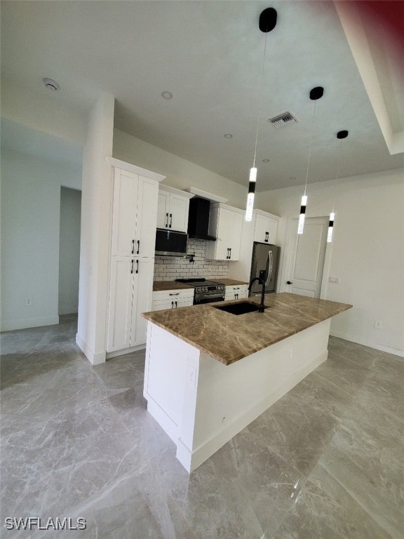 kitchen with appliances with stainless steel finishes, sink, decorative light fixtures, white cabinetry, and an island with sink