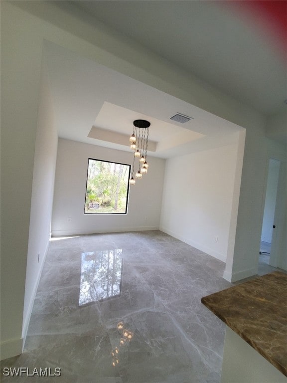 unfurnished room featuring a chandelier and a raised ceiling