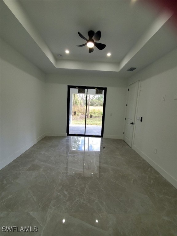 empty room featuring ceiling fan and a tray ceiling