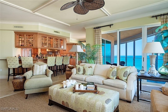 tiled living room with a water view, ceiling fan, and ornamental molding