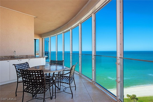 sunroom featuring a water view, a beach view, and sink