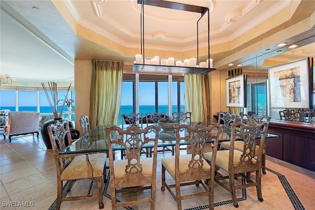 dining area with a water view, ornamental molding, and a raised ceiling