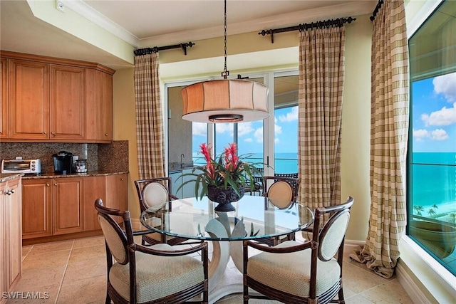 dining room featuring light tile patterned floors, ornamental molding, and a water view