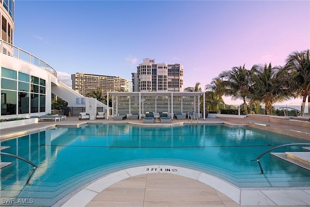 pool at dusk featuring a patio area