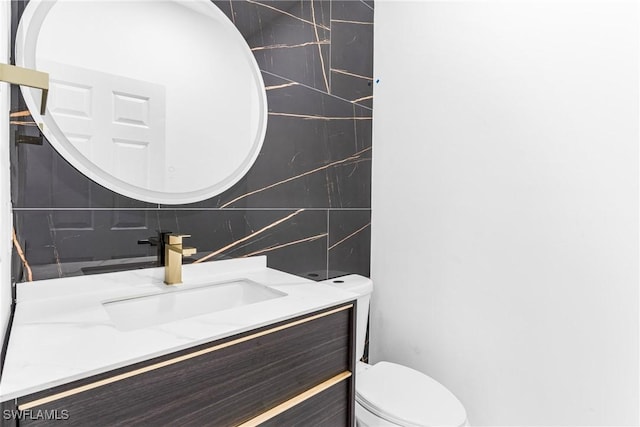 bathroom with vanity, tasteful backsplash, toilet, and tile walls