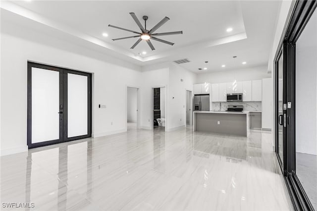 interior space featuring a tray ceiling, ceiling fan, and french doors