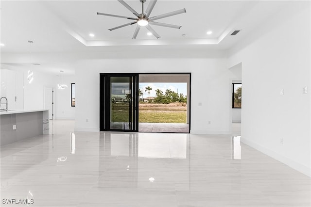 empty room featuring a raised ceiling and ceiling fan