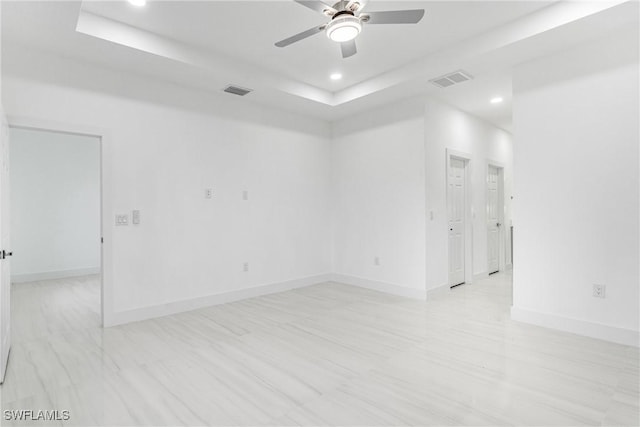 empty room with a raised ceiling and ceiling fan