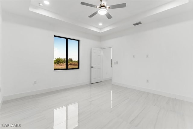 spare room featuring a tray ceiling and ceiling fan