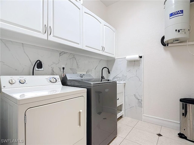 laundry area featuring water heater, independent washer and dryer, cabinets, and light tile patterned flooring