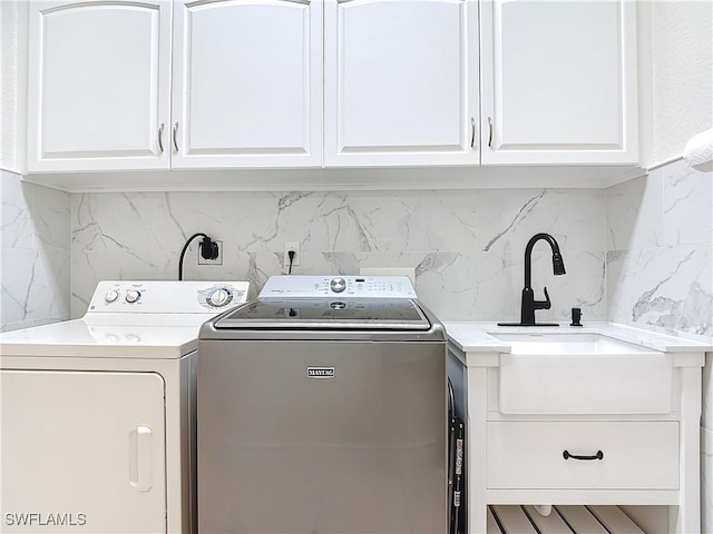 washroom with cabinets, washer and dryer, and sink