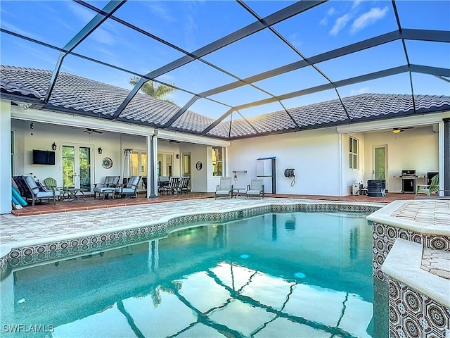 view of pool with a patio, ceiling fan, and glass enclosure