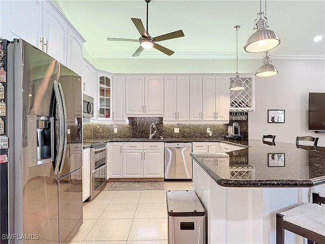 kitchen with appliances with stainless steel finishes, decorative light fixtures, white cabinetry, a kitchen bar, and kitchen peninsula