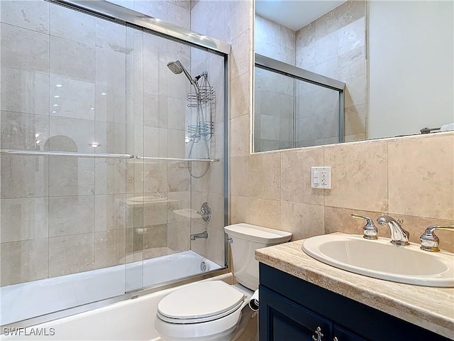 full bathroom featuring toilet, bath / shower combo with glass door, tile walls, vanity, and decorative backsplash