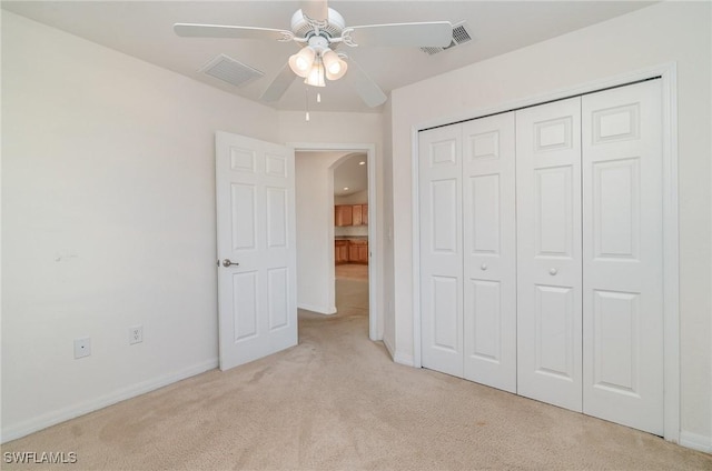 unfurnished bedroom featuring ceiling fan, a closet, and light carpet