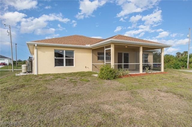 rear view of house featuring a sunroom and a yard