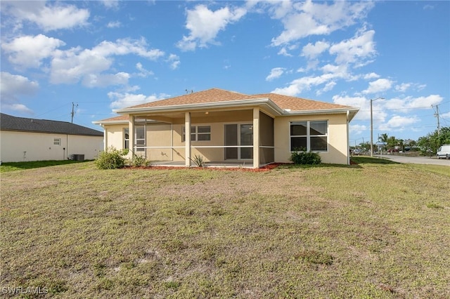 rear view of property featuring a lawn, a sunroom, and central AC