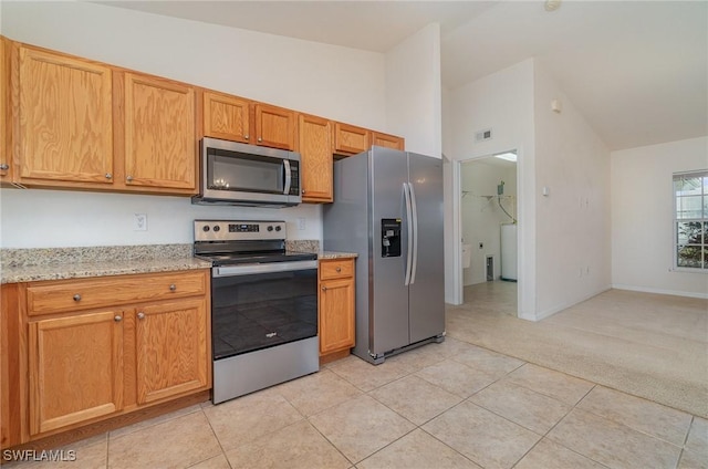 kitchen featuring lofted ceiling, light tile patterned flooring, light stone countertops, and stainless steel appliances