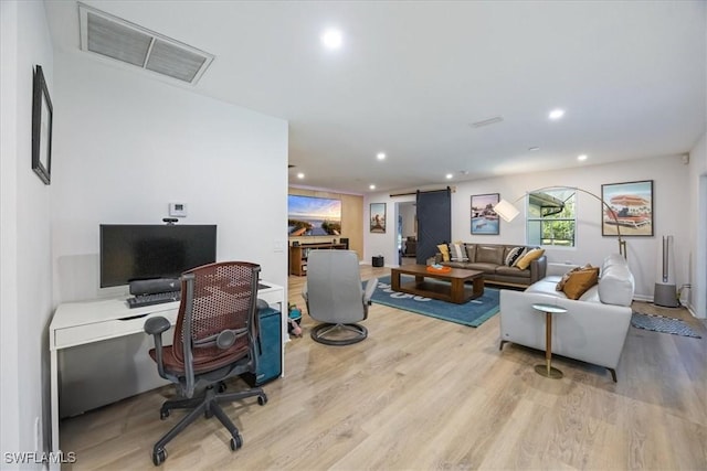 office area with a barn door and light hardwood / wood-style flooring