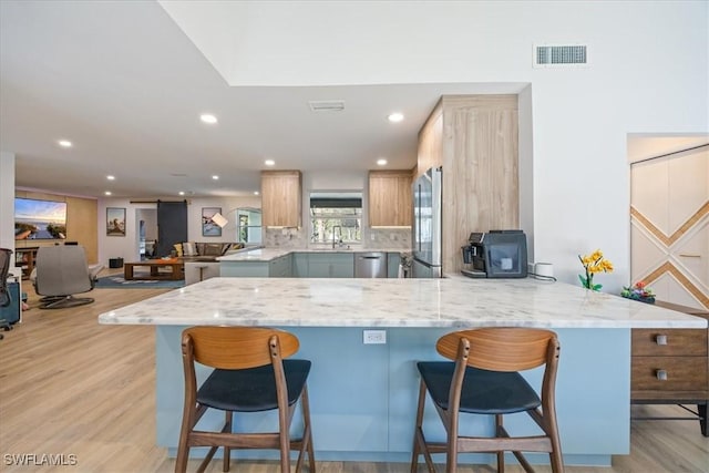 kitchen featuring recessed lighting, a breakfast bar, stainless steel appliances, visible vents, and a peninsula