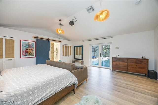 bedroom with access to outside, a barn door, vaulted ceiling, and light wood-type flooring