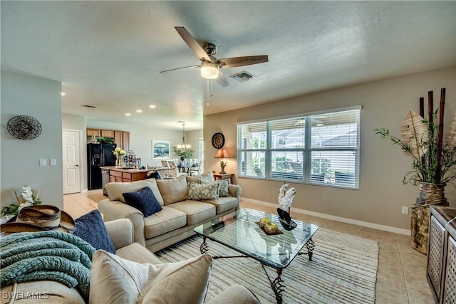 living room featuring ceiling fan with notable chandelier and light tile patterned floors