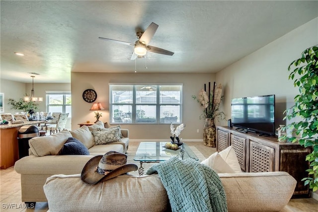 living room featuring ceiling fan with notable chandelier, plenty of natural light, and light tile patterned flooring