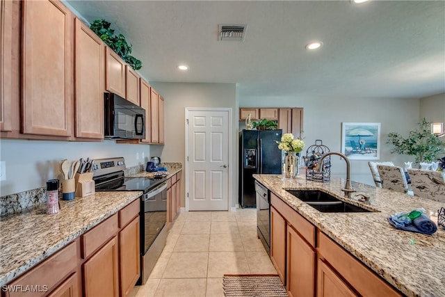 kitchen with light tile patterned flooring, sink, light stone countertops, and black appliances