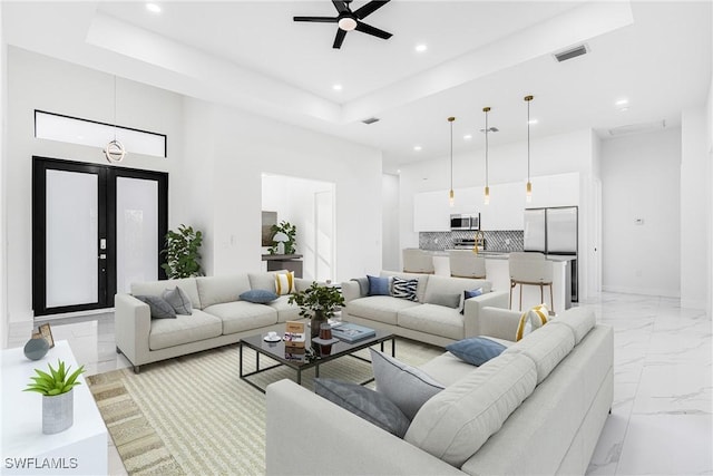 living room featuring a tray ceiling, ceiling fan, and a high ceiling