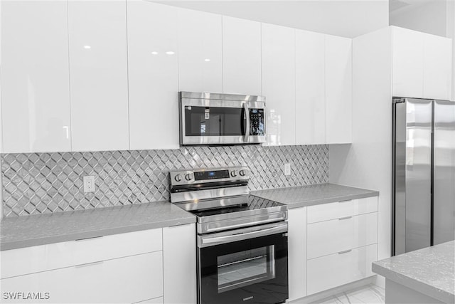 kitchen featuring white cabinets, appliances with stainless steel finishes, and tasteful backsplash