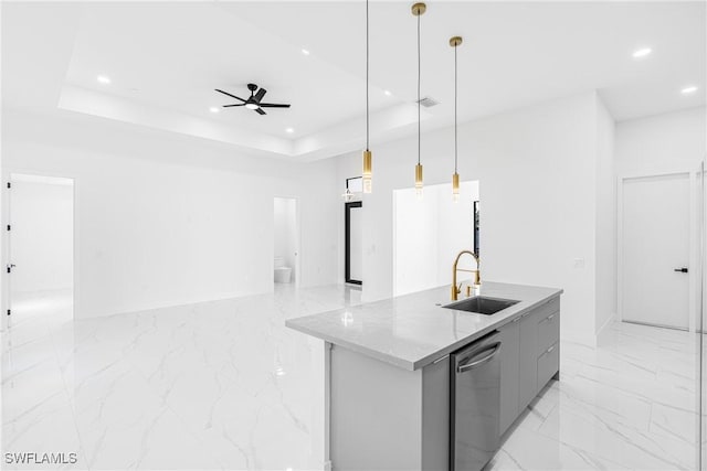 kitchen featuring a tray ceiling, a kitchen island with sink, sink, and dishwasher