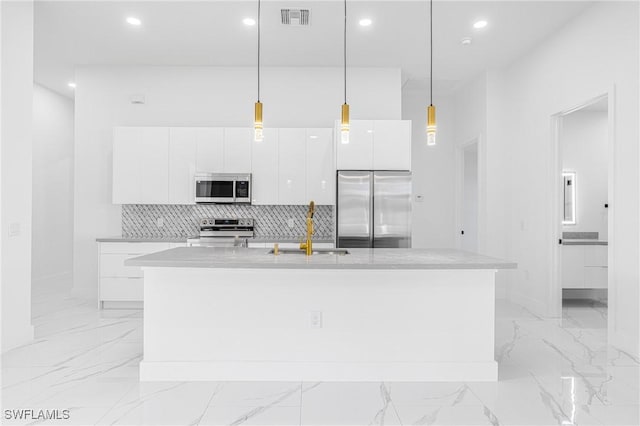 kitchen with sink, stainless steel appliances, an island with sink, pendant lighting, and white cabinets