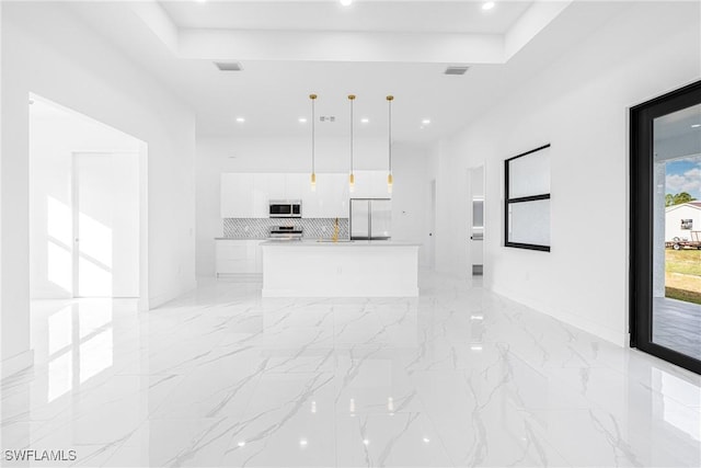 kitchen with white cabinetry, stainless steel appliances, tasteful backsplash, decorative light fixtures, and a kitchen island with sink