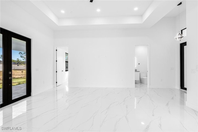 unfurnished room with a raised ceiling, a towering ceiling, and french doors