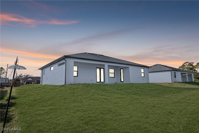 back house at dusk with a lawn