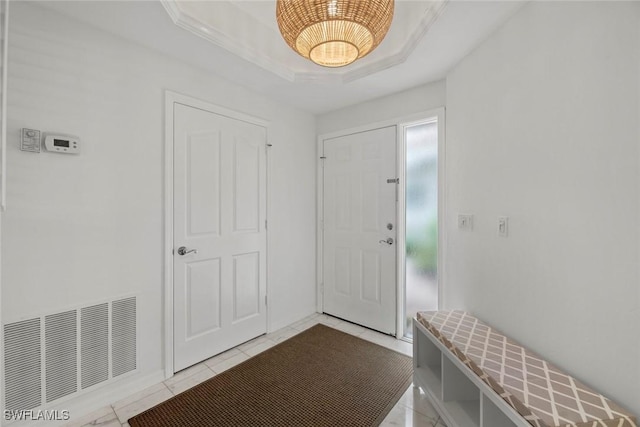 tiled entryway with a raised ceiling and crown molding