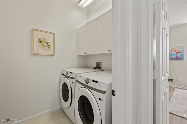 laundry room featuring cabinets, light tile patterned floors, and washing machine and clothes dryer