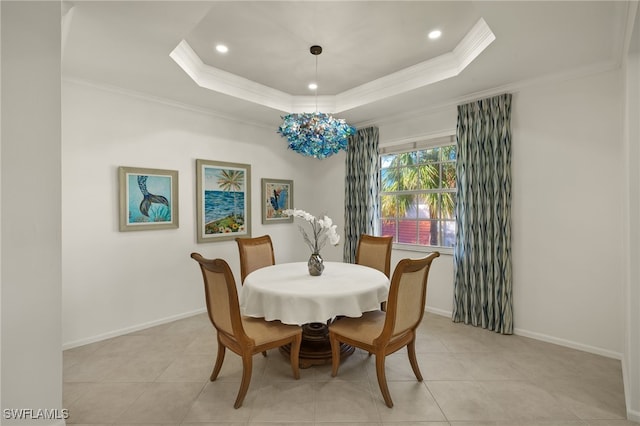 tiled dining room with ornamental molding and a tray ceiling