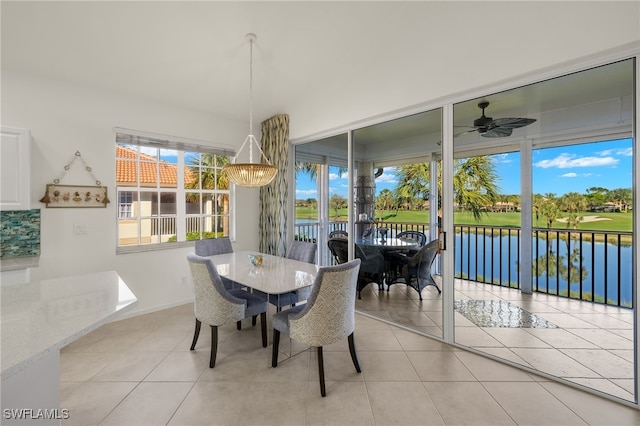 dining room featuring ceiling fan, a water view, and light tile patterned floors