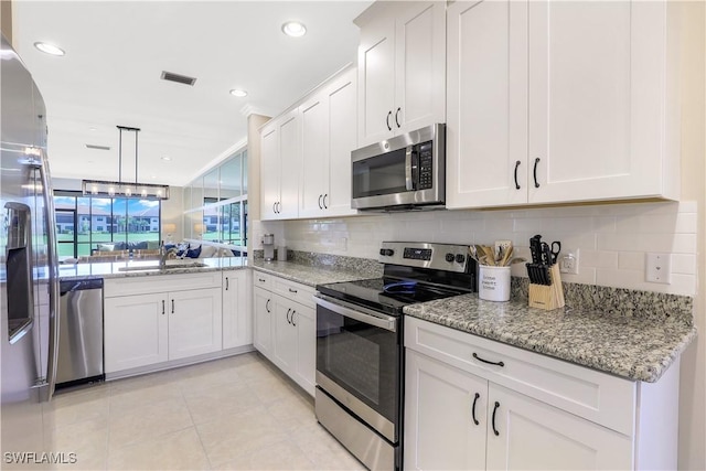 kitchen with backsplash, stainless steel appliances, white cabinetry, and sink