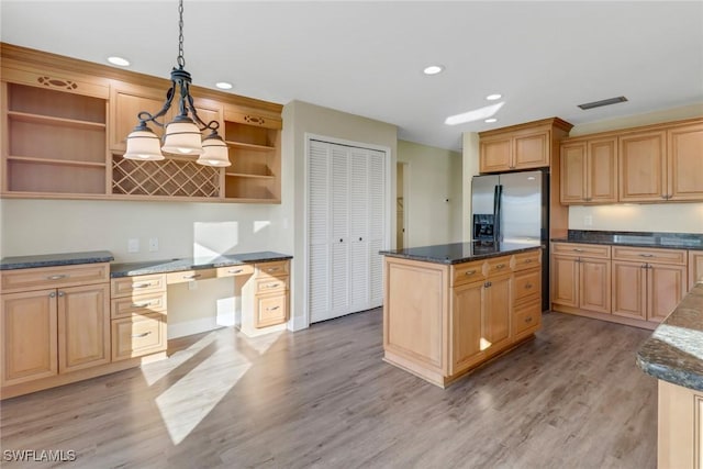 kitchen featuring pendant lighting, built in desk, a kitchen island, and light hardwood / wood-style flooring