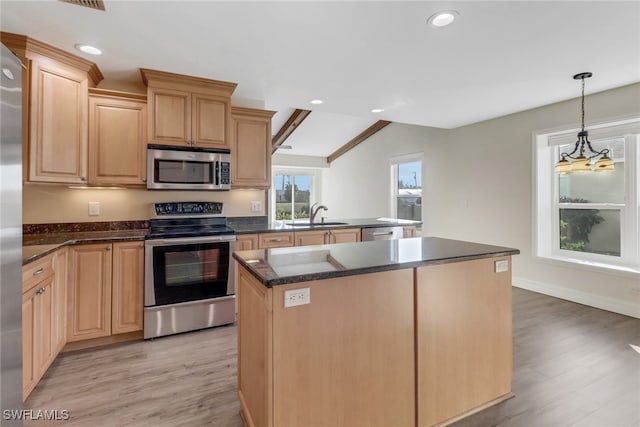 kitchen with appliances with stainless steel finishes, sink, a center island, decorative light fixtures, and light brown cabinetry