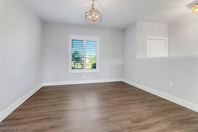 spare room featuring dark hardwood / wood-style flooring and an inviting chandelier