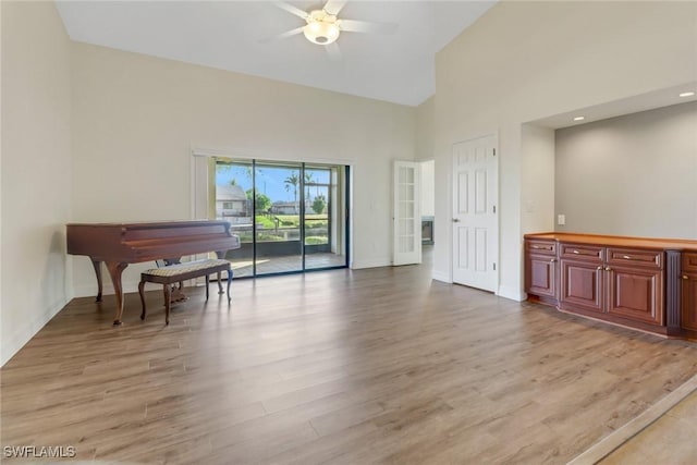 empty room featuring ceiling fan, high vaulted ceiling, and light hardwood / wood-style floors