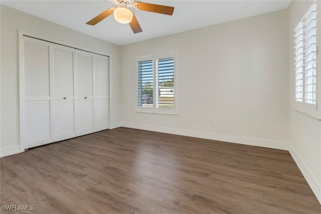 unfurnished bedroom featuring ceiling fan, a closet, and dark wood-type flooring