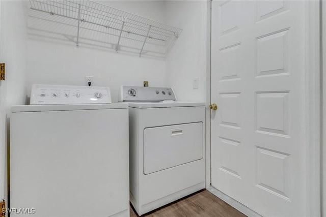 clothes washing area featuring separate washer and dryer and wood-type flooring